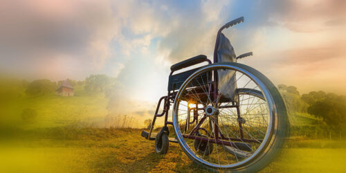 Pusty wózek inwalidzki na tle pejzarzu z zachodzącym słońcem.