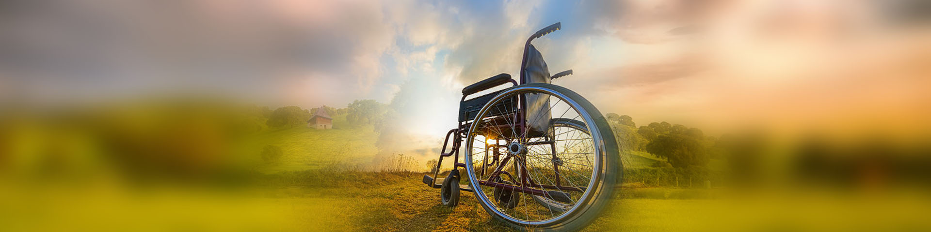 Pusty wózek inwalidzki na tle pejzarzu z zachodzącym słońcem.