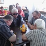 Seniorzy grają w bierki przy stoliku.