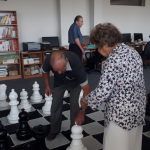 Seniorzy przesuwają po szachownicy wielkie pionki.