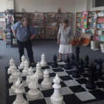 Grupa seniorów gra w szachy o kilkudziesięciu centymetrach wysokości.